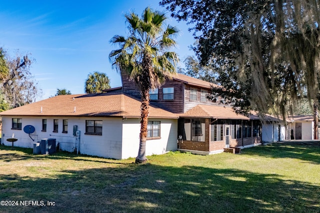 back of house featuring a lawn and a sunroom