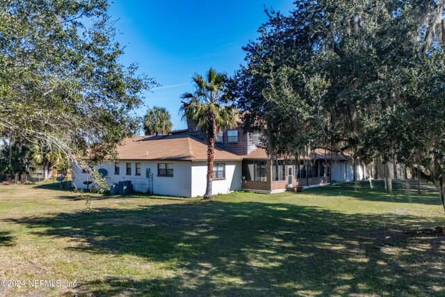 rear view of property featuring a yard and a sunroom