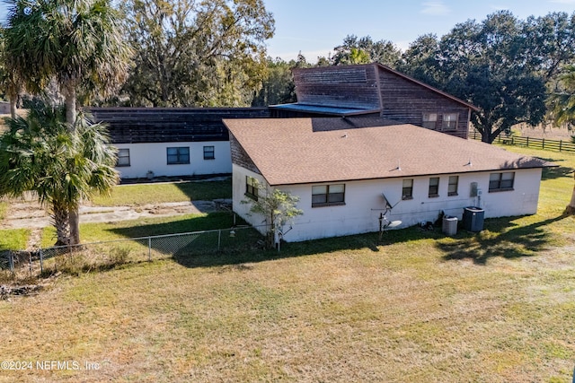 back of property with a lawn and cooling unit