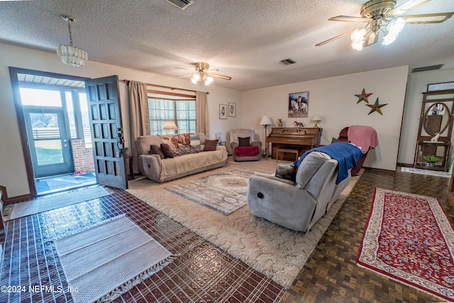 living room with ceiling fan with notable chandelier, a textured ceiling, and a wealth of natural light