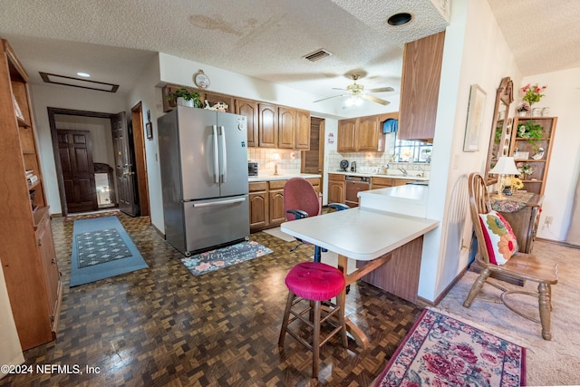 11289 SW 85th Ave, Hampton, FL 32044 - kitchen with freestanding refrigerator, a textured ceiling, dishwasher, brown cabinetry, and light countertops
