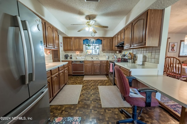 kitchen featuring decorative backsplash, a textured ceiling, stainless steel appliances, ceiling fan, and sink