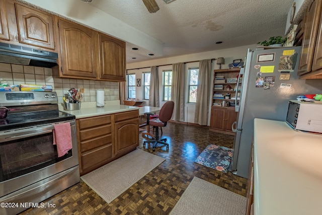 kitchen featuring dark parquet flooring, backsplash, extractor fan, a textured ceiling, and stainless steel range with electric stovetop