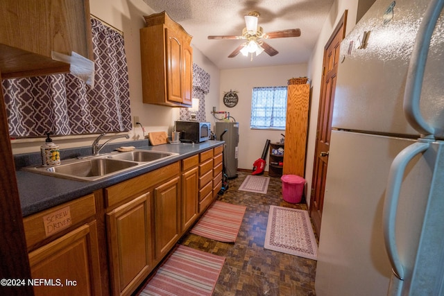 kitchen with ceiling fan, sink, white fridge, and a textured ceiling