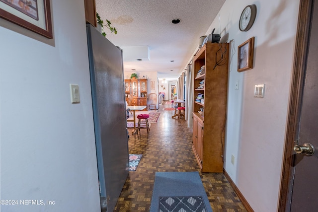 hallway with dark parquet flooring and a textured ceiling