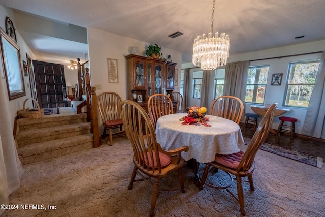 carpeted dining room featuring a notable chandelier and a textured ceiling