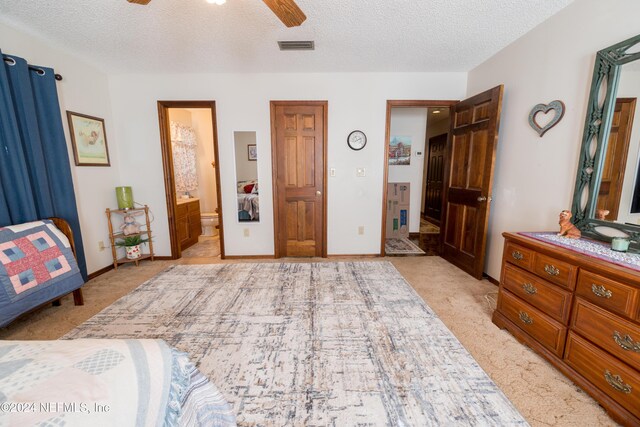 carpeted bedroom with ensuite bathroom, ceiling fan, and a textured ceiling