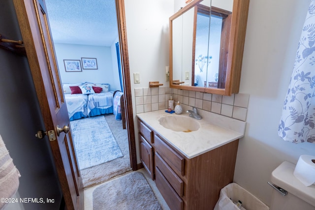 bathroom with backsplash, vanity, toilet, and a textured ceiling