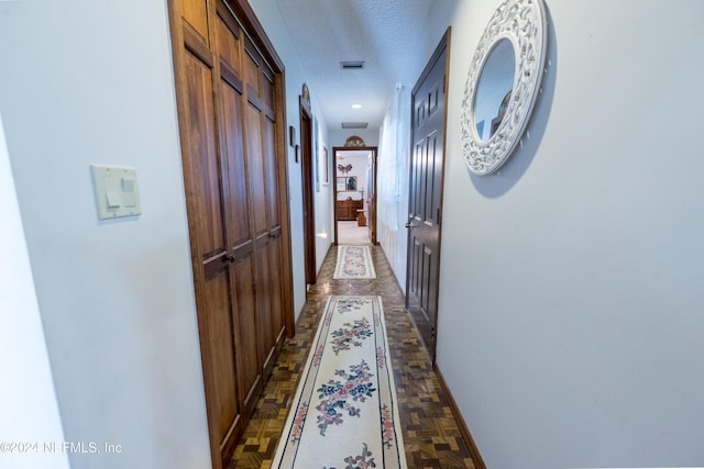 hallway featuring parquet floors and a textured ceiling