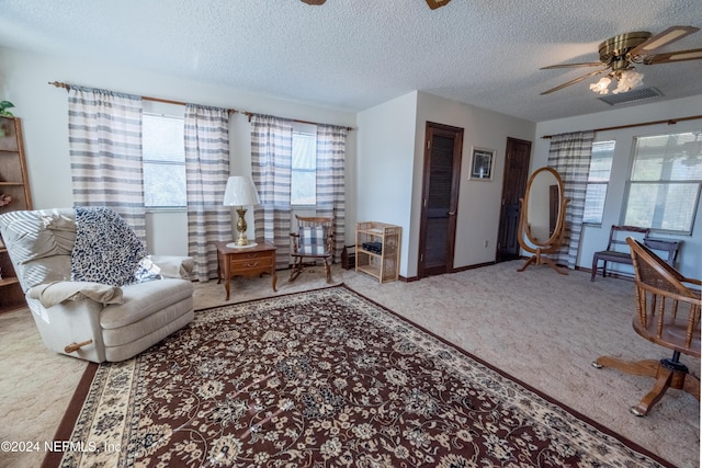 carpeted living room featuring a textured ceiling, ceiling fan, and a healthy amount of sunlight