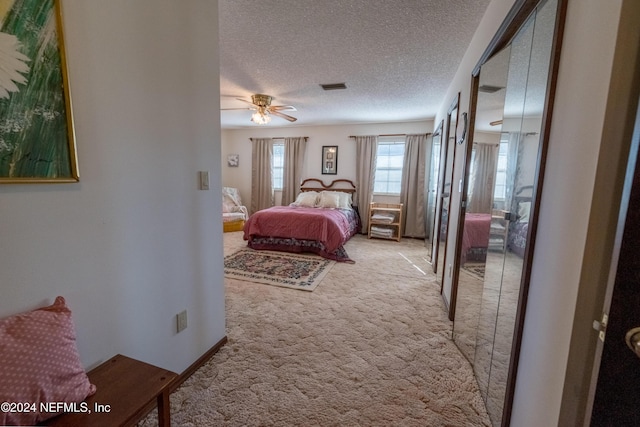 carpeted bedroom featuring ceiling fan and a textured ceiling