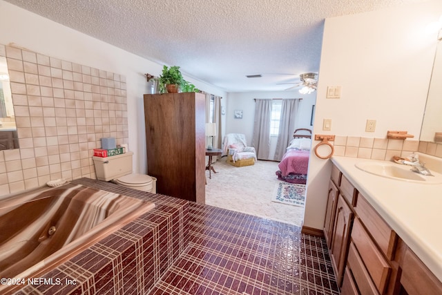 bathroom featuring vanity, ceiling fan, toilet, a textured ceiling, and tile walls