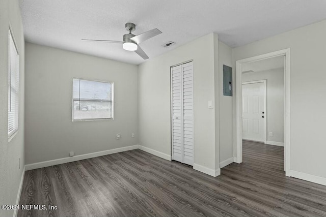 unfurnished bedroom featuring electric panel, ceiling fan, a closet, and dark hardwood / wood-style floors