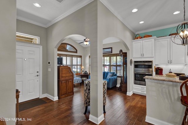 kitchen with ceiling fan with notable chandelier, dark hardwood / wood-style flooring, white cabinetry, and ornamental molding