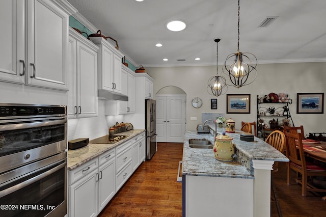 kitchen with white cabinetry, dark wood-type flooring, an island with sink, a breakfast bar, and appliances with stainless steel finishes