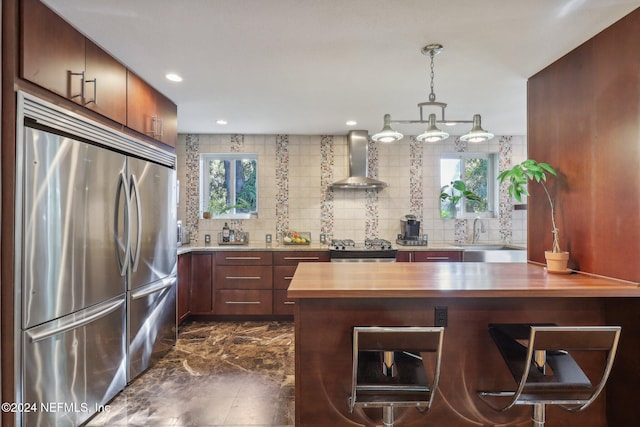 kitchen featuring a wealth of natural light, wall chimney exhaust hood, wooden counters, and appliances with stainless steel finishes