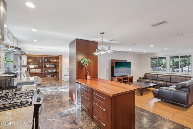 kitchen featuring hanging light fixtures, dark wood-type flooring, wine cooler, wooden counters, and island exhaust hood