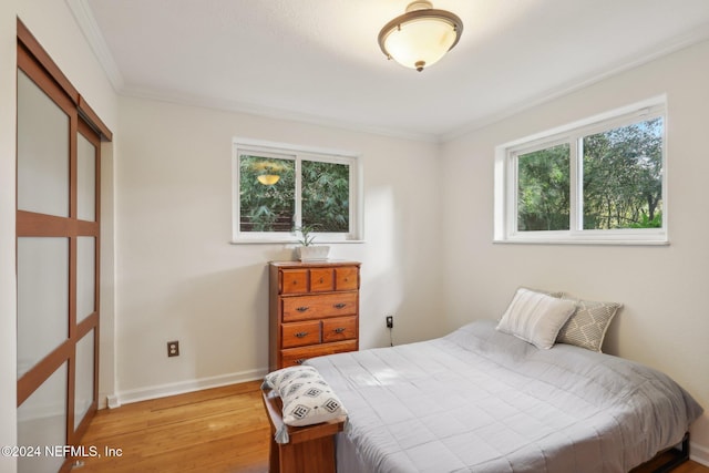 bedroom with light wood-type flooring and crown molding