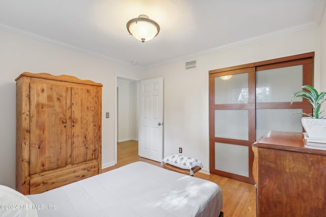 bedroom featuring crown molding and light hardwood / wood-style floors