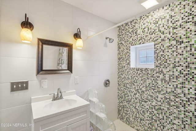 bathroom with a tile shower, vanity, tasteful backsplash, and tile walls