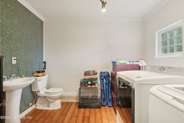 washroom with hardwood / wood-style flooring, crown molding, and washing machine and clothes dryer