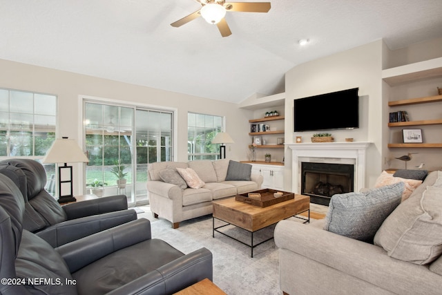 living room with ceiling fan, a healthy amount of sunlight, lofted ceiling, and built in features