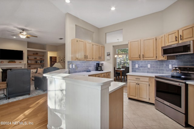 kitchen with sink, light tile patterned floors, appliances with stainless steel finishes, light brown cabinetry, and decorative backsplash