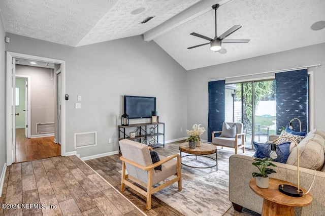 living room featuring lofted ceiling with beams, ceiling fan, wood-type flooring, and a textured ceiling