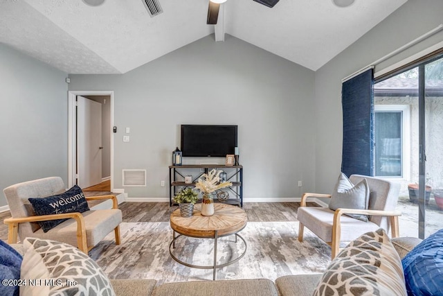 living room with vaulted ceiling with beams, ceiling fan, and light wood-type flooring