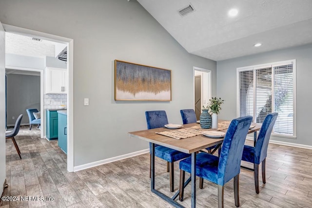 dining space with light hardwood / wood-style flooring and lofted ceiling