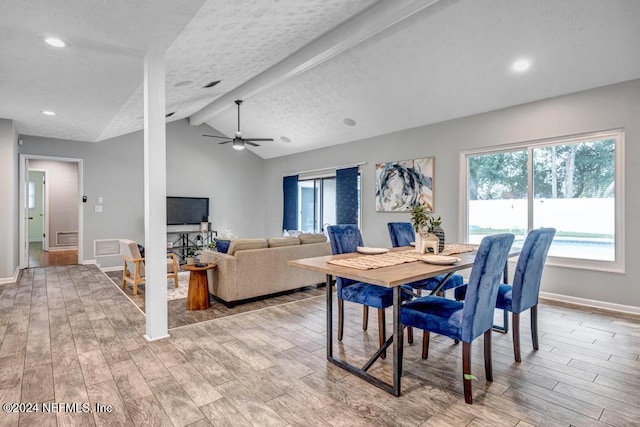 dining area with vaulted ceiling with beams, ceiling fan, light hardwood / wood-style floors, and a textured ceiling