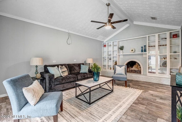 living room with a textured ceiling, vaulted ceiling with beams, hardwood / wood-style flooring, and ceiling fan