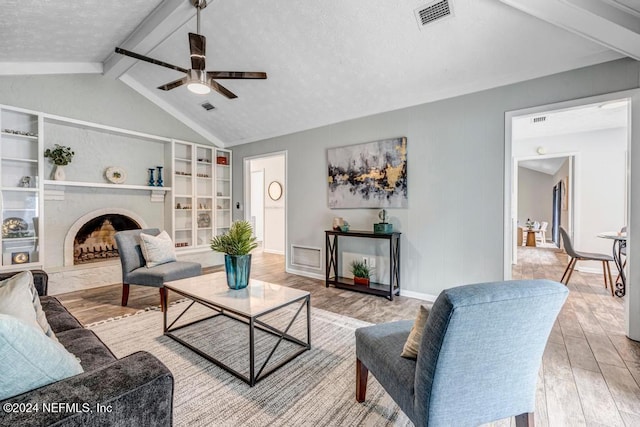 living room featuring vaulted ceiling with beams, ceiling fan, a textured ceiling, and hardwood / wood-style flooring