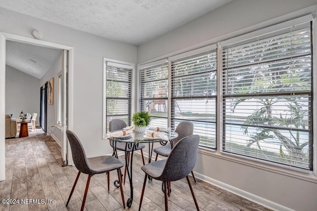 dining area with plenty of natural light, vaulted ceiling, and hardwood / wood-style flooring