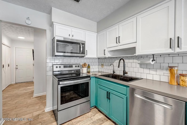 kitchen featuring sink, stainless steel appliances, light hardwood / wood-style floors, a textured ceiling, and white cabinets