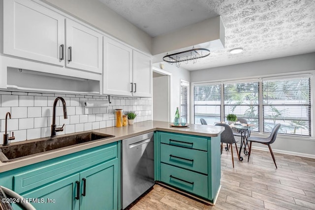 kitchen with white cabinets, sink, light hardwood / wood-style flooring, stainless steel dishwasher, and kitchen peninsula