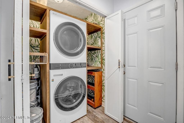 laundry room with stacked washer and dryer and light hardwood / wood-style floors