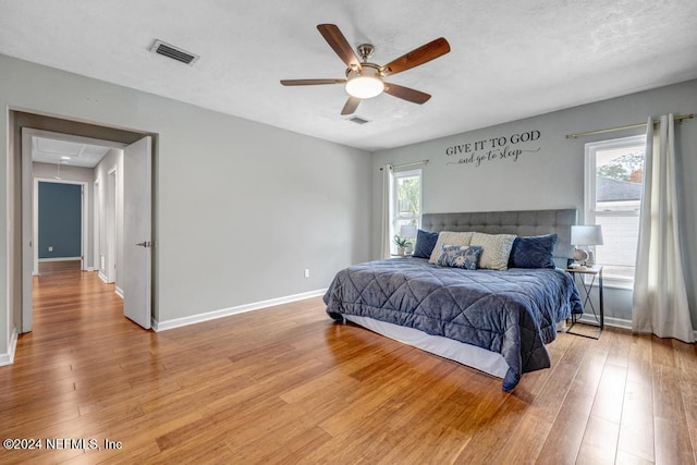 bedroom with light hardwood / wood-style floors, multiple windows, and ceiling fan