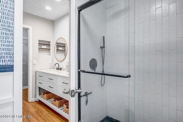 bathroom featuring hardwood / wood-style floors, vanity, and a shower with shower door