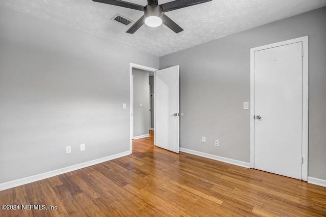 empty room with ceiling fan, light hardwood / wood-style floors, and a textured ceiling