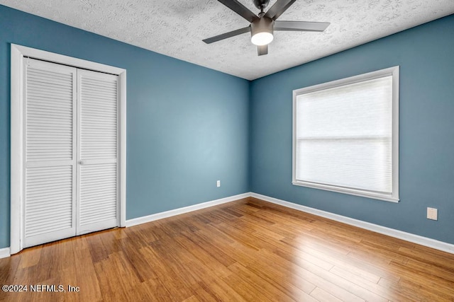 unfurnished bedroom featuring wood-type flooring, a textured ceiling, a closet, and ceiling fan