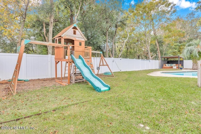 view of jungle gym with a yard and a fenced in pool