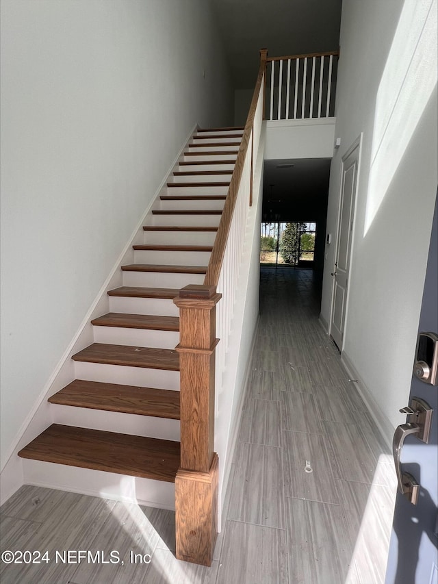 stairs with wood-type flooring and a high ceiling