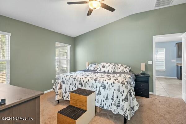 carpeted bedroom with vaulted ceiling, multiple windows, and ceiling fan