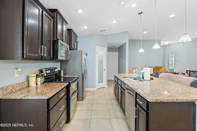 kitchen featuring light tile patterned flooring, appliances with stainless steel finishes, decorative light fixtures, a kitchen island with sink, and light stone countertops