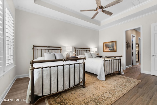 bedroom with a tray ceiling, ceiling fan, hardwood / wood-style floors, and ornamental molding