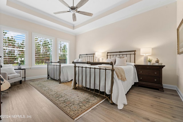 bedroom with a tray ceiling, ceiling fan, crown molding, and wood-type flooring