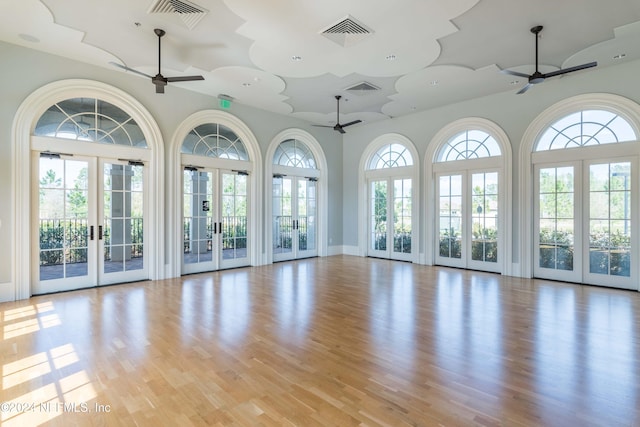 empty room with a wealth of natural light, french doors, and light wood-type flooring