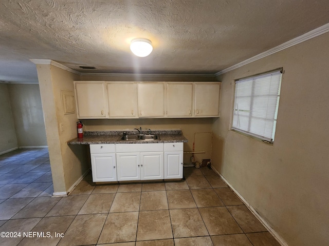 kitchen featuring sink, light tile patterned flooring, crown molding, a textured ceiling, and white cabinets