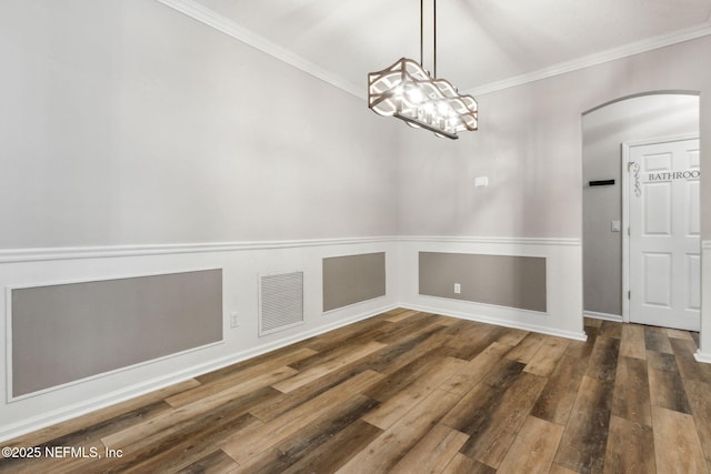 unfurnished dining area with dark wood-type flooring, crown molding, and a notable chandelier